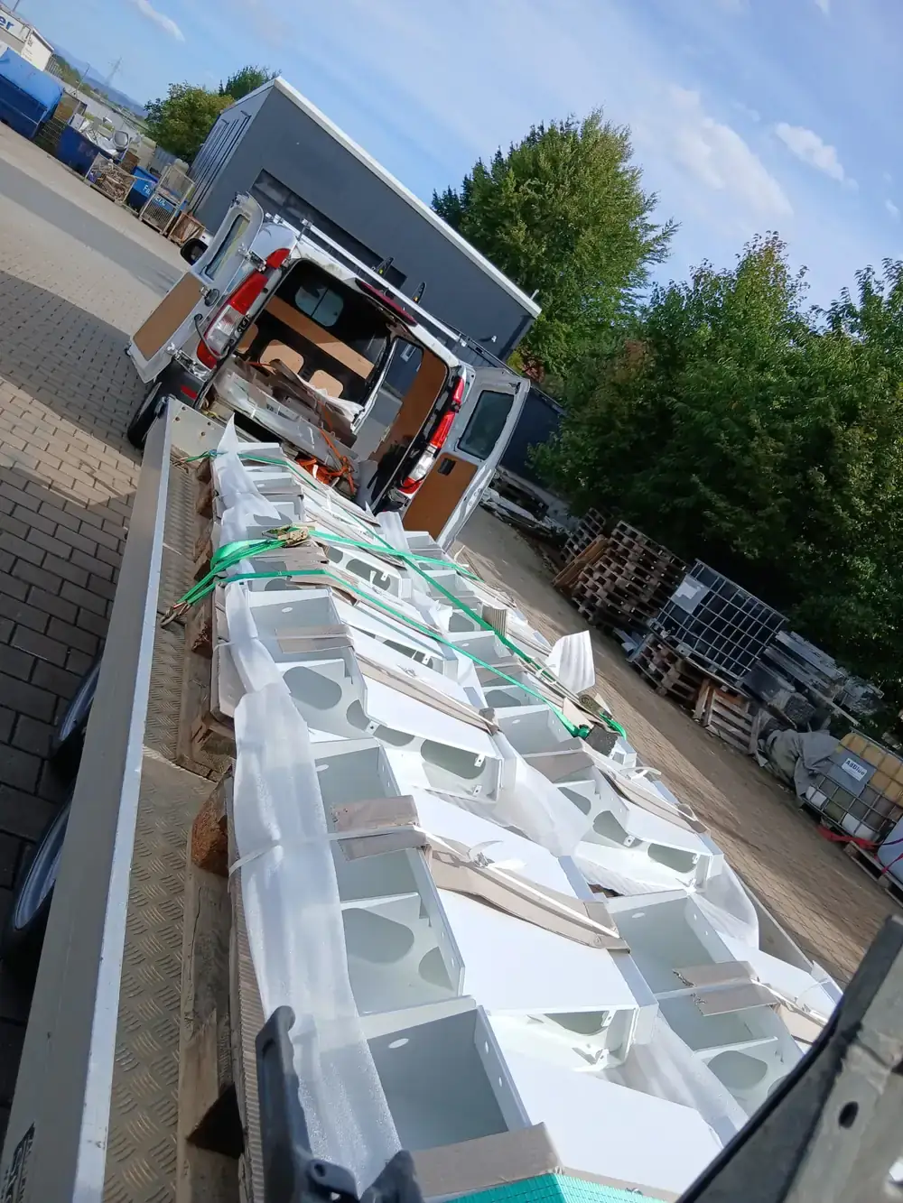 Frisch beschichtete Serienteile in Verkehrsweiß, verpackt und verzurrt auf dem Anhänger zur Auslieferung